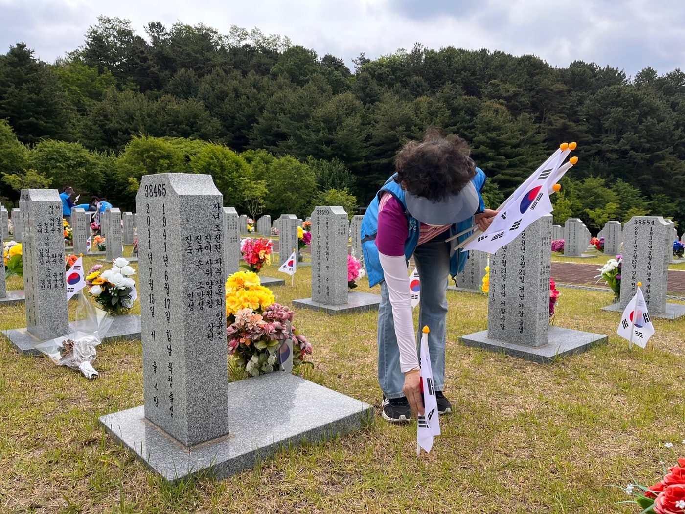 [사진설명] 대전자생봉사단원이 국립대전현충원에서 순국 선열들이 잠들어 있는 묘비 옆에 태극기를 꽂고 있다..jpg